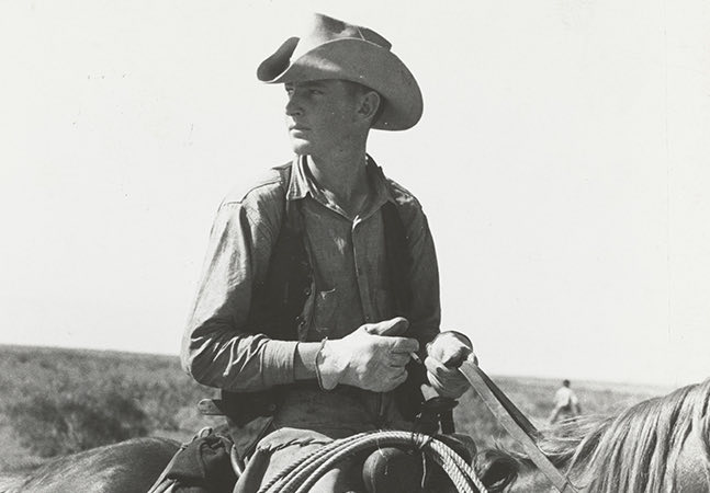 man with a cowboy hat on a horse in a black and white photo
