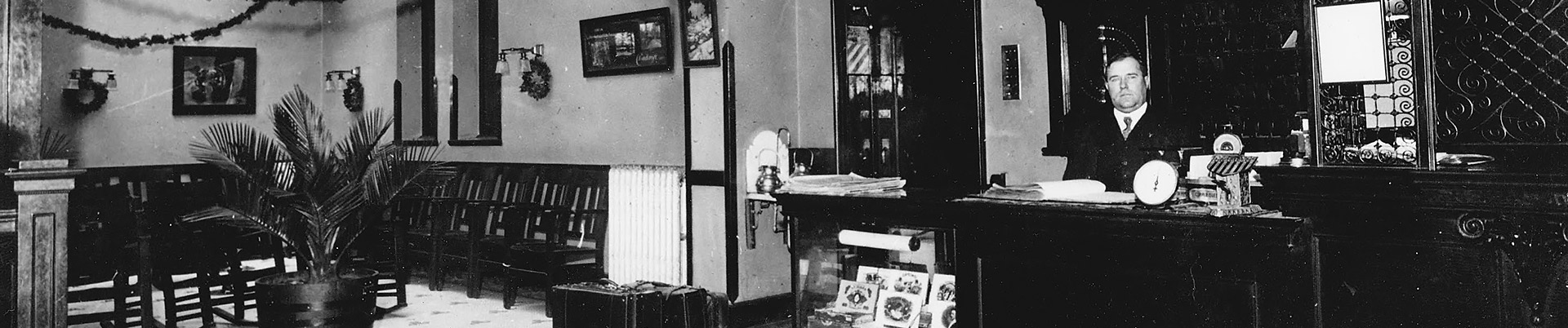 black and white image of the lobby at the copper queen and a man standing behind the reception desk