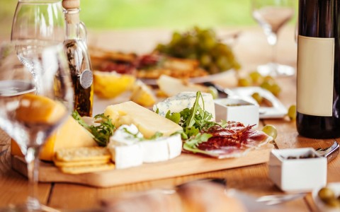 View of a Cheese-plate with some crackers and a bottle of wine.