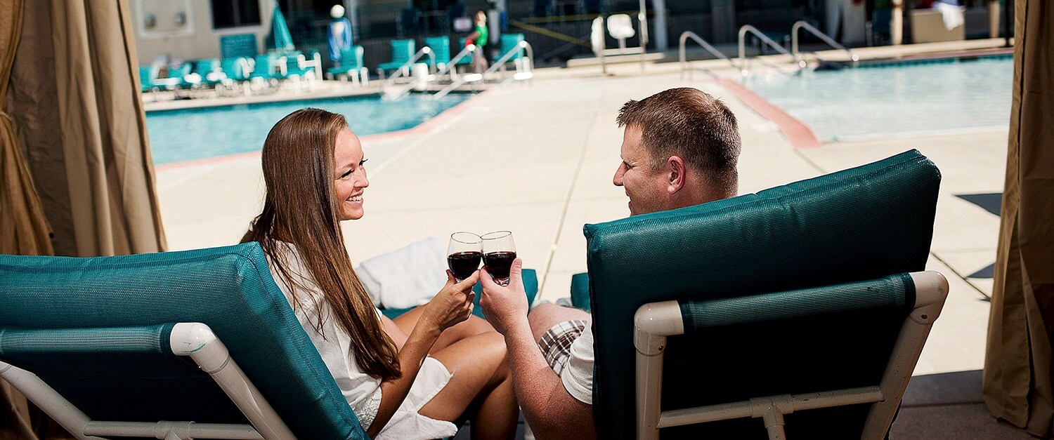 a couple drinking wine by the pool at night