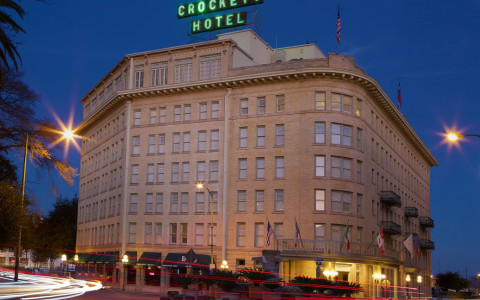 crockett hotel with neon green sign on top lit up at night