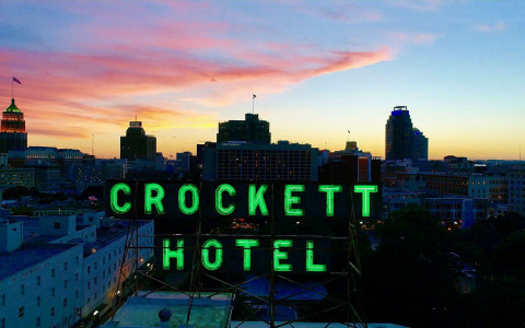 neon green crocket hotel sign on top of the building at night