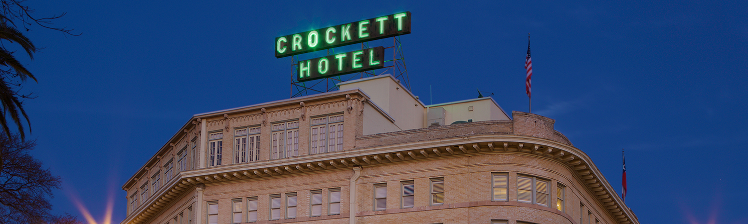 a neon green crockett hotel sign on top of the hotel