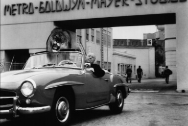 b&w photo of man riding in older car