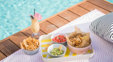 nachos and guacamole by the pool with a drink