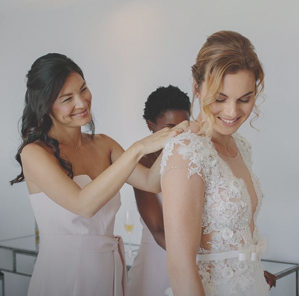 bridesmaid zipping up bride's dress