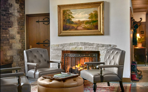a lit fireplace with two gray leather chairs