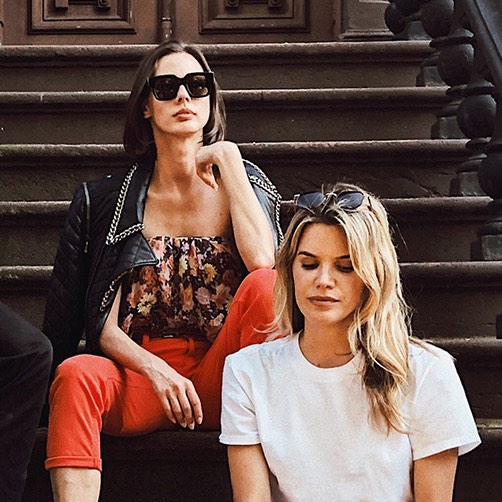 two city girls sitting on steps of a townhouse