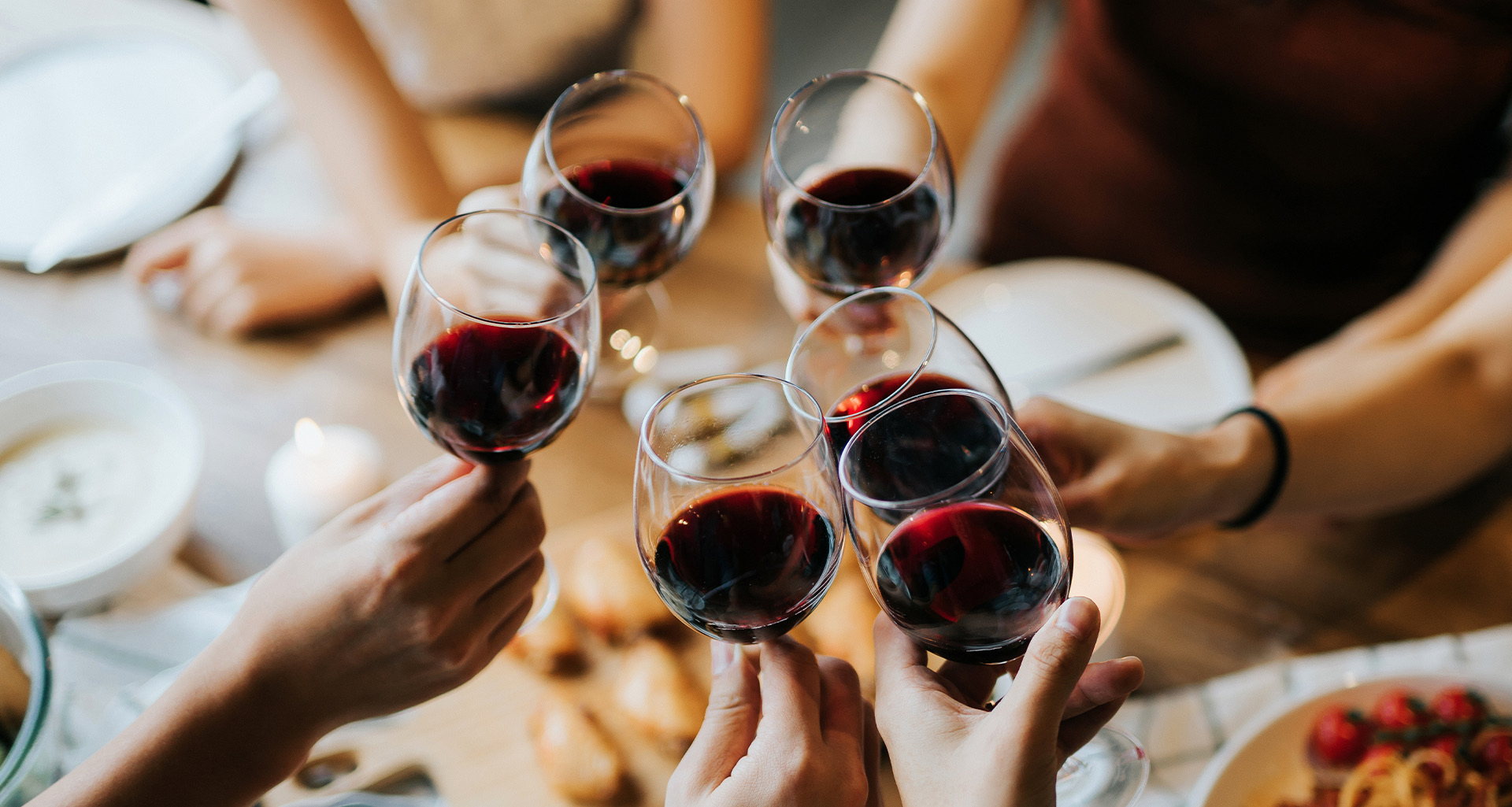 group of people clinking their glasses of red wine