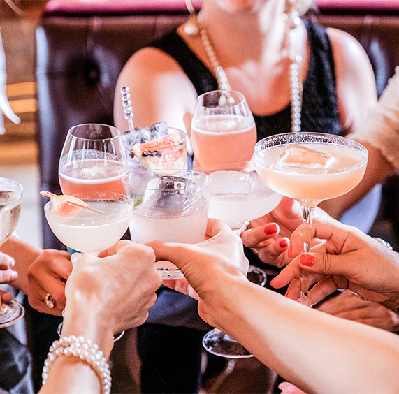 group of well-dressed people clinking their elegant cocktails