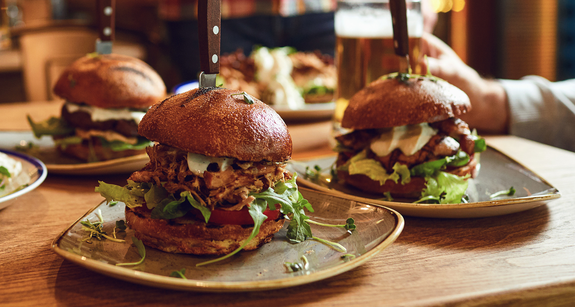 three dishes with large burgers