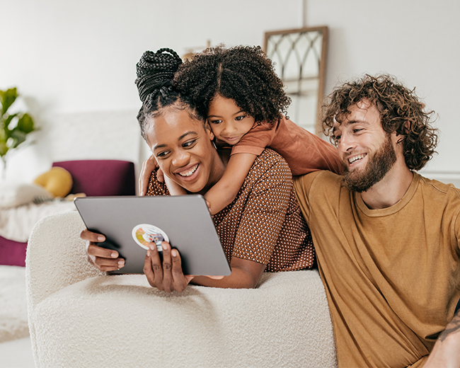 small family laughing and looking at an ipad