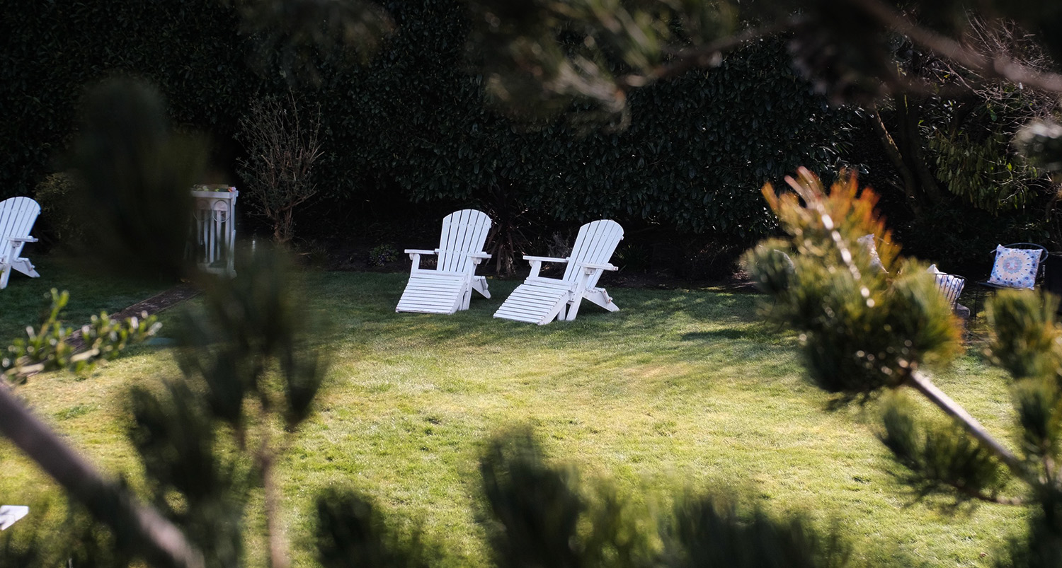 White adirondeck chairs in the grassy area with the sun shining.