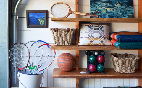 Sports equipment in a garage with wooden shelves.