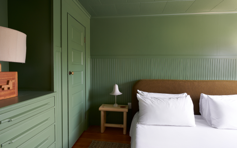 The light green colored walls and built-in furniture  in a room with a large bed.