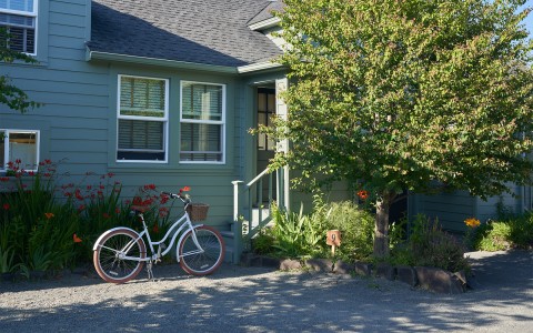 A white bicycle parked next to the entrance of a light green house.