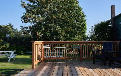 A wooden outdoor deck with chairs and tables to relax.
