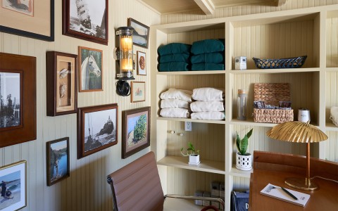 An office area with artwork hanging on the walls and fresh towels on the shelves.