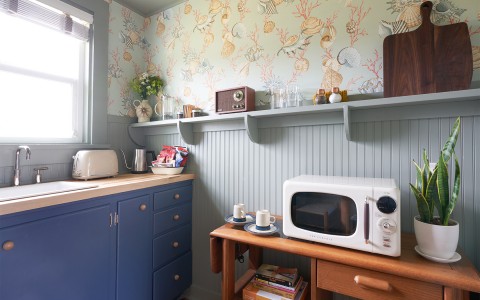 A small blue and light green colored kitchen with retro appliances.