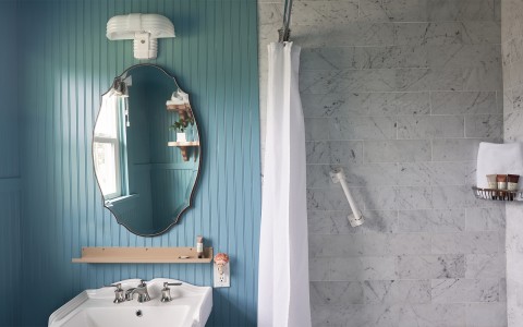 A light blue colored bathroom with a walk-in shower and the sun shining in from the left.