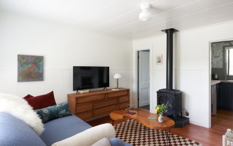 A room with a wood burning stove and a flat panel television on top of a wooden dresser.
