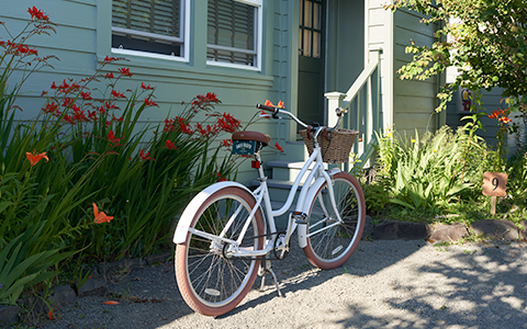 A white bicycle parked next to an entrance of a light green house.