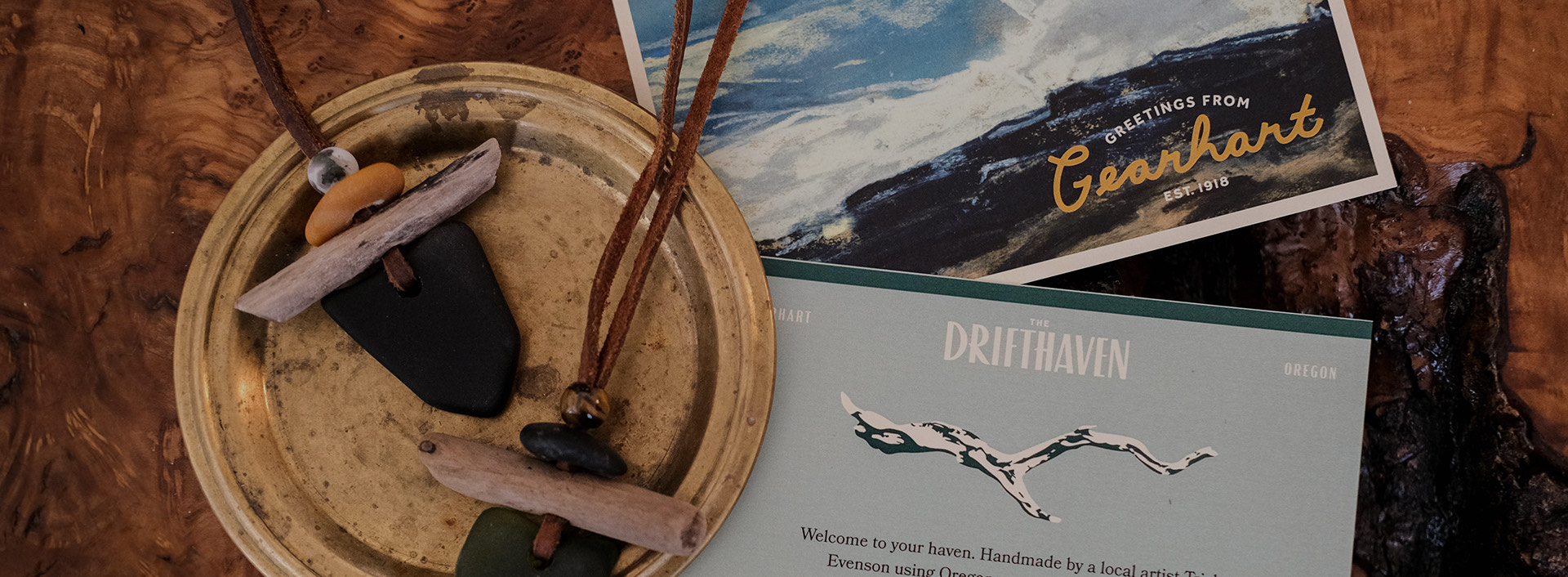 Two postcards and a small golden plate with homemade jewelry on top of it.