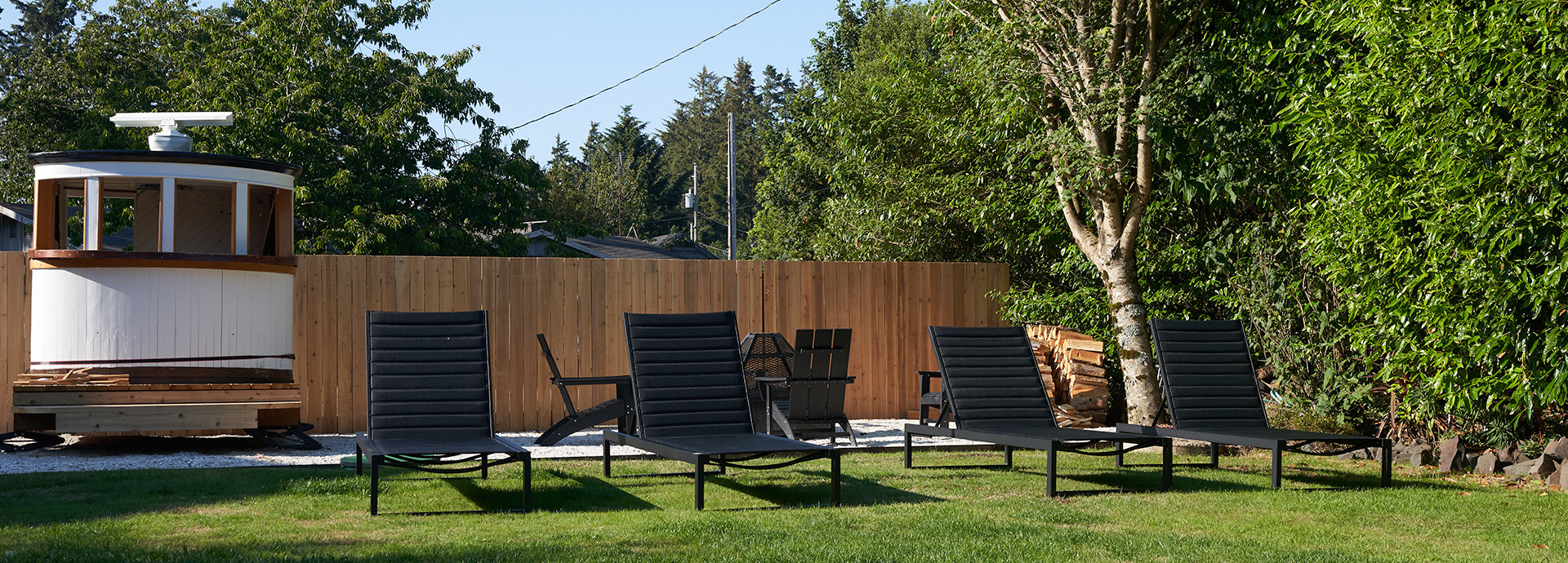 Black lounge chairs in a grassy area outside.