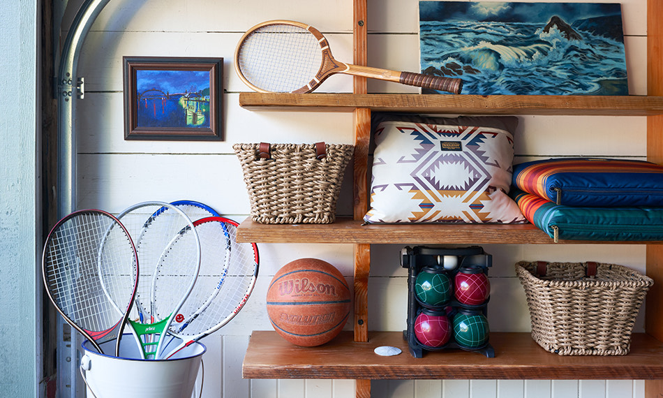 Wooden shelving with baskets, sports equipment, and outdoor blankets.