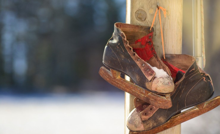 old, worn out ice skates hanging on wooden post