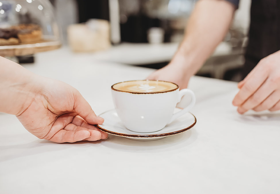 view of someone handing a cup of coffee to another person