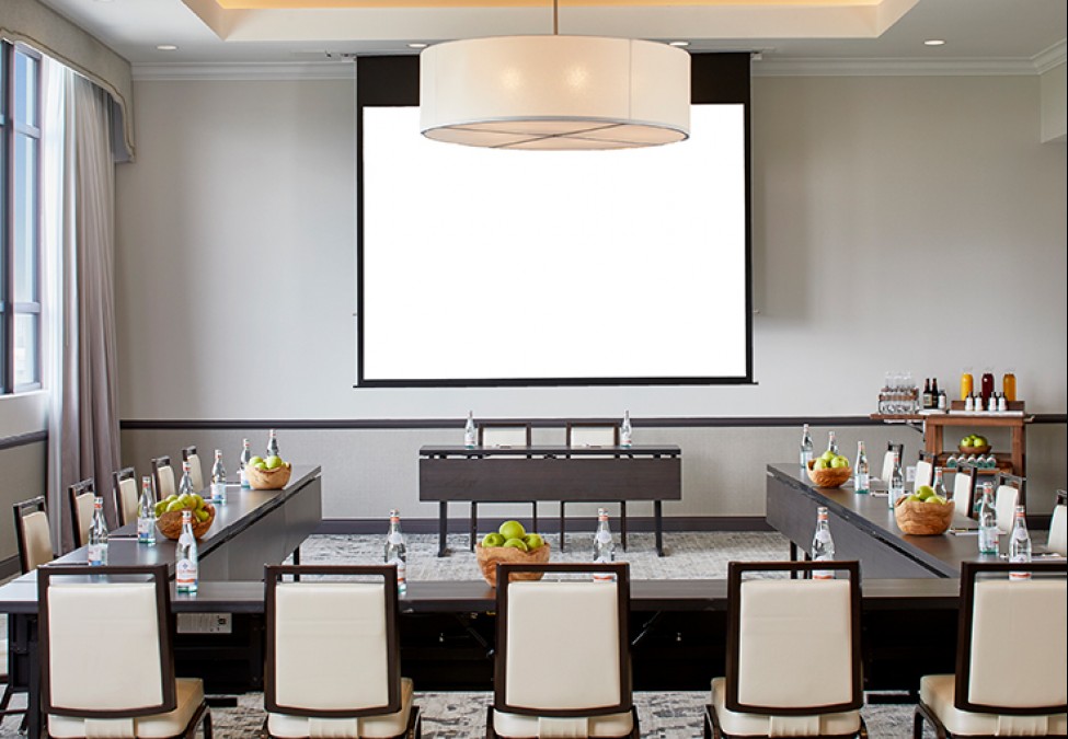 executive board room with tables and chairs set up and a big ceiling light 