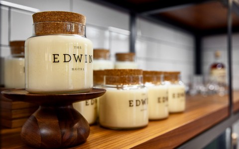 glass jars topped with corks with the edwin hotel name on the front of the jar