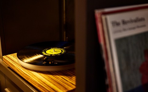 close up of a record player with a vinyl on it and books out of focus