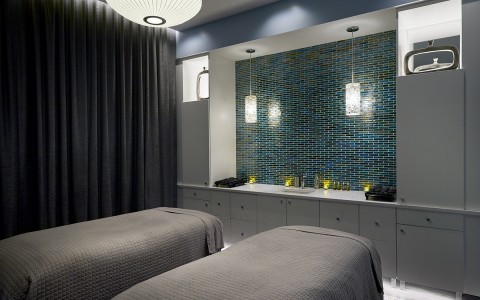 a dimly lit spa room with two spa beds and grey sheets on them 