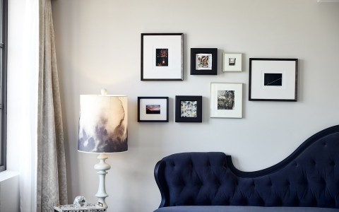 different sizes of photo frames above the couch and lamp on the left 