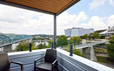 view of the blue bridge and water from a room with two patio chairs in it 