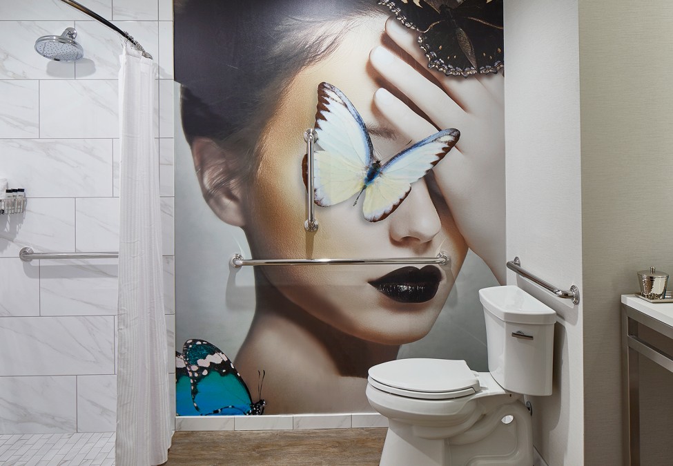 bathroom with a woman and butterfly mural with a view of the toilet and shower