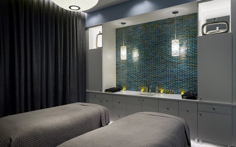dim lit spa room with two spa beds and white cabinets 