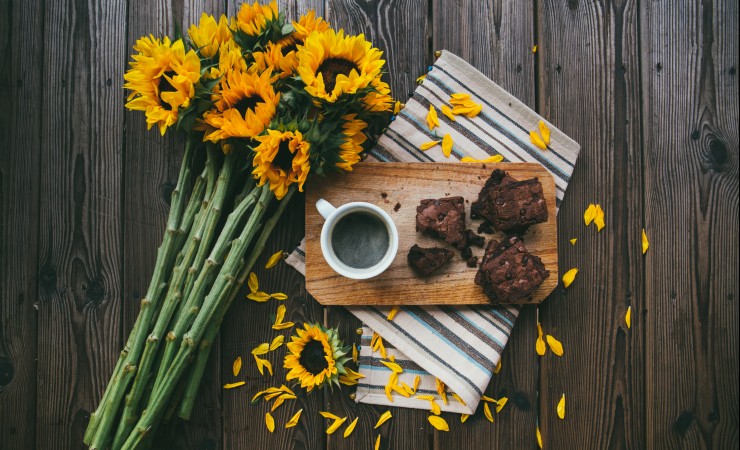 sunflowers next to a tray of brownies with coffee