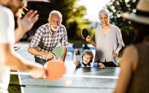 View of two grandparents playing ping pong with their grandson