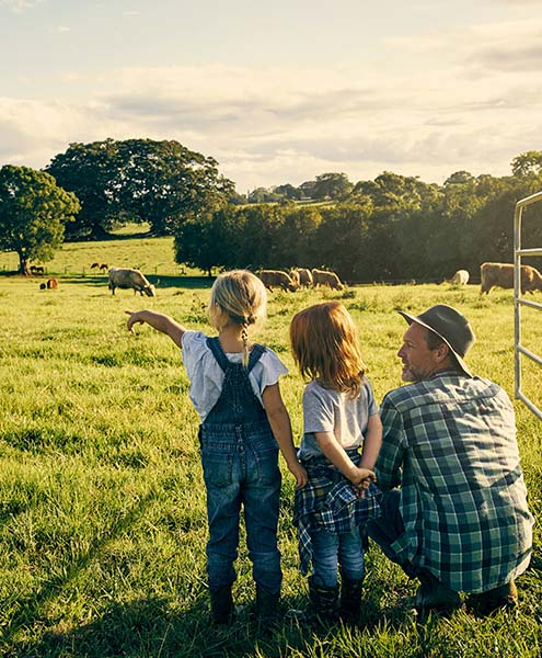 View of two little girls and their dad on a farm