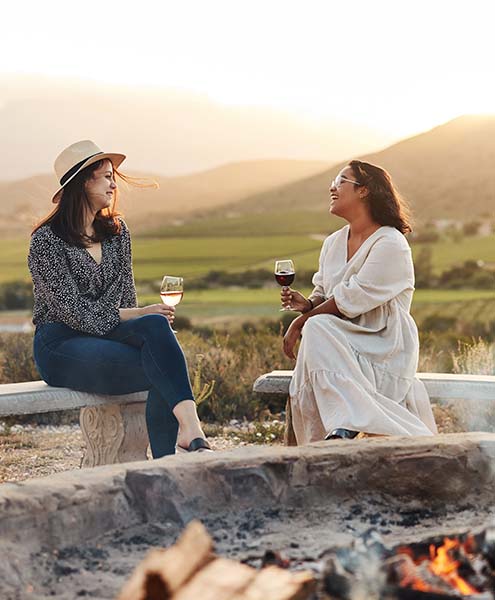 View of two girl friends talking and drinking wine outdoors