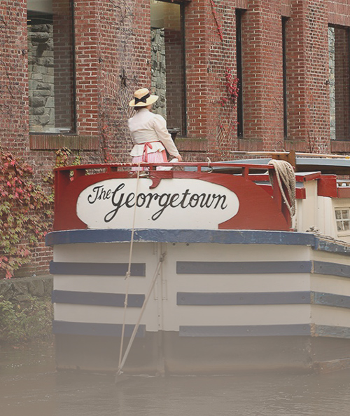 Woman wearing sun hat riding boat with The Georgetown written on it 