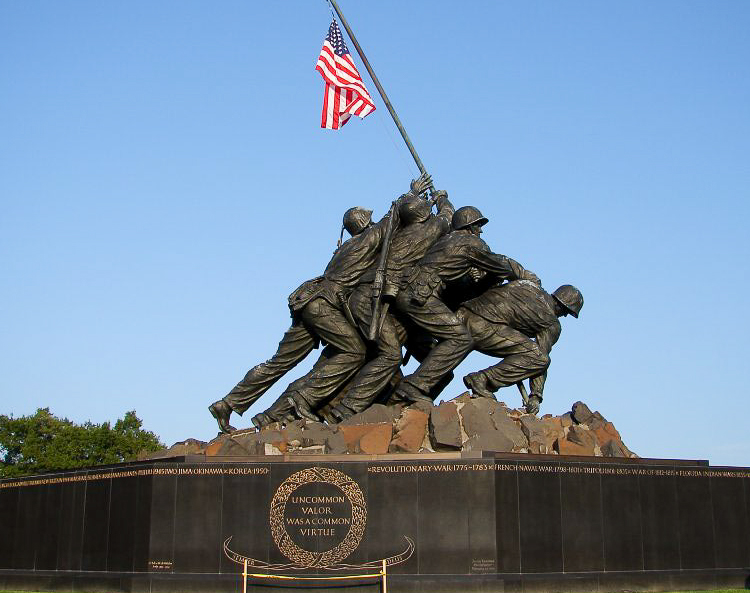 soldiers holding up American flag in a monument 