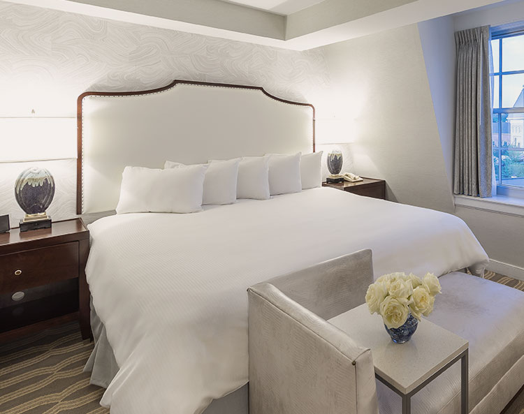 king bed with white bedspread and 5 pillows