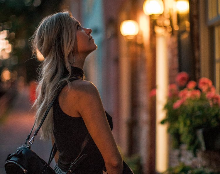 woman looking up at colorful buildings with lanterns