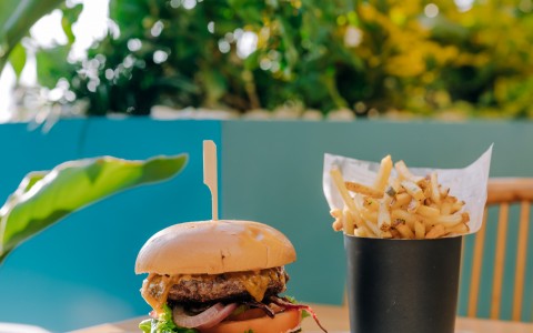 burger with cup of fries on a wooden board