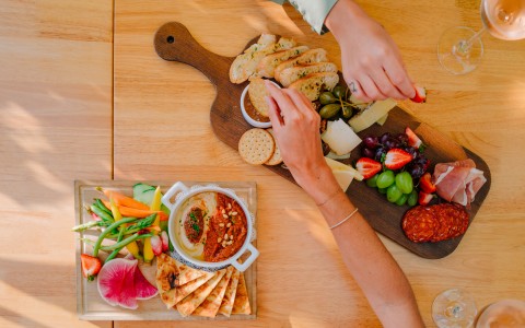 aerial view of a charcuterie board and a board with hummus and veggies