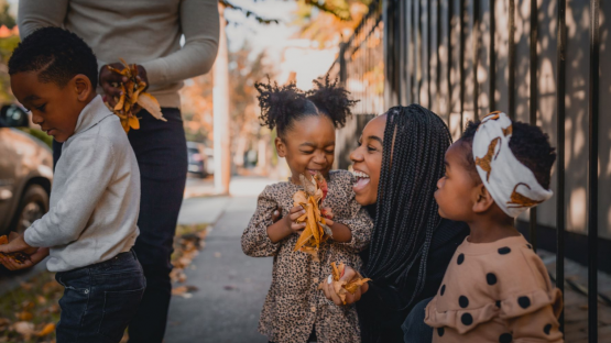 view of a family playing with fall leaves